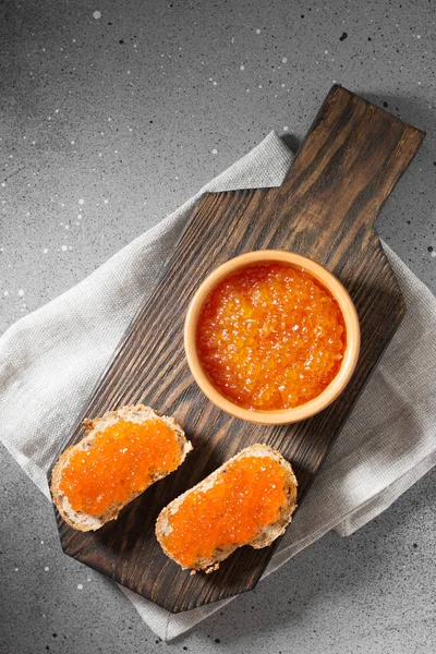 Red caviar in ceramic bowl on wooden Board on grey background. Top view — Stock Image Red Caviar Ceramic Bowl Wooden Board Grey Background Top View Stock Image