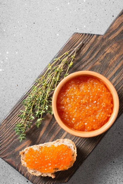 Red caviar in ceramic bowl on wooden Board on grey background — Stock Image Red Caviar Ceramic Bowl Wooden Board Grey Background Stock Image