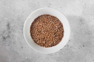 Keten tohumu gri mutfak masası üzerinde beyaz bir kase. Organik sağlık gıda