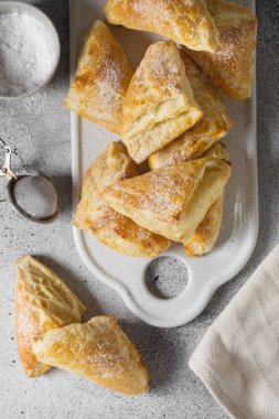 Gri bir tablo üzerinde beyaz bir tepsi üzerinde puf çörekler. Tatlı hamur işleri