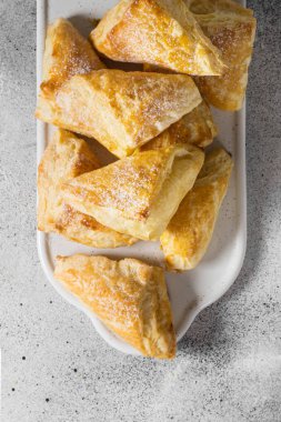 Gri bir tablo üzerinde beyaz bir tepsi üzerinde puf çörekler. Tatlı hamur işleri