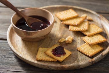 Ahşap arka plan üzerinde ahşap bir tabakta vişne reçelli kraker. Rustik tarzı