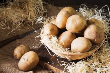 Çiğ patates ahşap bir masa üzerinde bir sepet içinde. Rustik tarzı