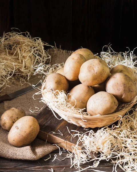 Raw potatoes in a basket on a wooden table. Rustic style