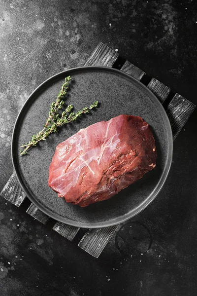 Siyah bir arka plan üzerinde siyah bir tabakta et çiğ Ren geyiği