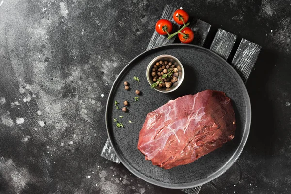 Çiğ Ren geyiği eti koyu arka plan üzerinde siyah bir plaka üzerinde