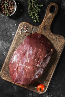 Çiğ Ren geyiği eti koyu arka plan üzerinde ahşap tahta üzerinde