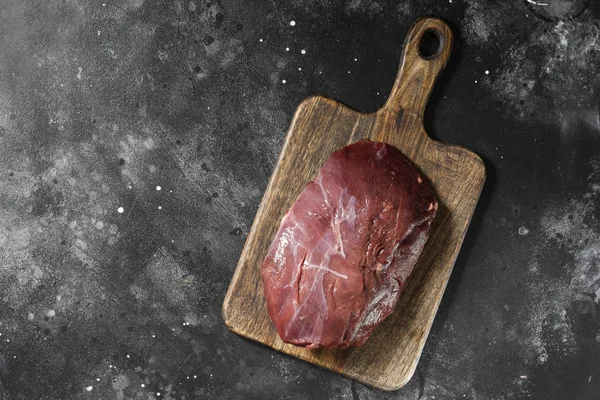 Çiğ Ren geyiği eti koyu arka plan üzerinde ahşap tahta üzerinde