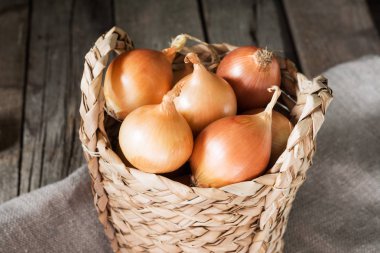 Ahşap bir masa üzerinde bir sepet içinde soğan. Rustik tarzı