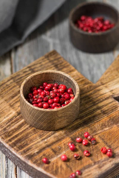 Pink pepper in a wooden bowl on a wooden Board. Rustic style