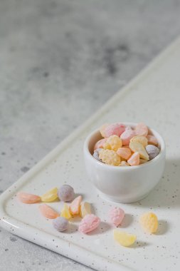 Hafif bir arka plan üzerinde beyaz bir tabak renkli şekerler