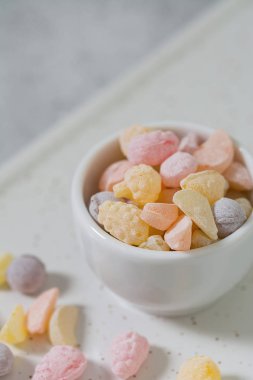 Hafif bir arka plan üzerinde beyaz bir tabak renkli şekerler