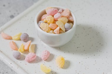 Hafif bir arka plan üzerinde beyaz bir tabak renkli şekerler