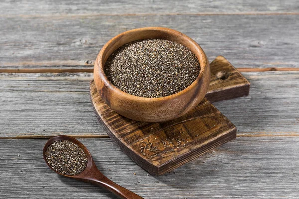 Gri ahşap bir masa üzerinde ahşap bir kase chia tohumları. Sağlıklı beslenme. Rustik stil