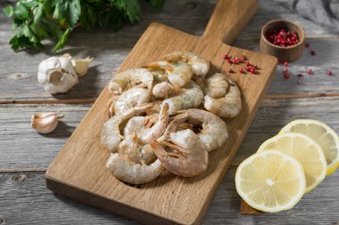 Gri ahşap bir masa üzerinde ahşap bir tahta üzerinde ham kaplan karides. Rustik stil