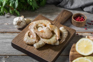 Gri ahşap bir masa üzerinde ahşap bir tahta üzerinde ham kaplan karides. Rustik stil