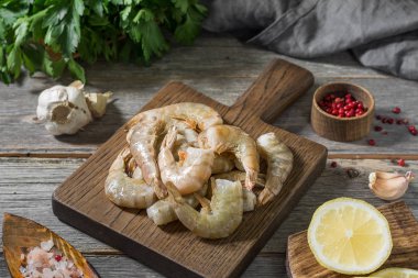 Gri ahşap bir masa üzerinde ahşap bir tahta üzerinde ham kaplan karides. Rustik stil