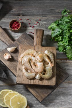 Gri ahşap bir masa üzerinde ahşap bir tahta üzerinde ham kaplan karides. Rustik stil