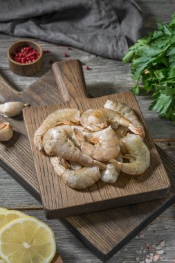 Gri ahşap bir masa üzerinde ahşap bir tahta üzerinde ham kaplan karides. Rustik stil