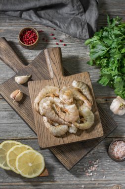 Gri ahşap bir masa üzerinde ahşap bir tahta üzerinde ham kaplan karides. Rustik stil