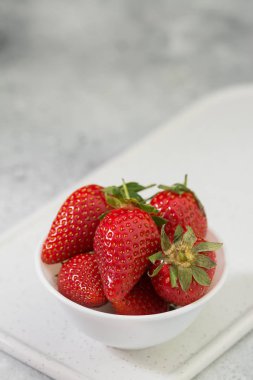 Açık arka planda beyaz tabakta çilek