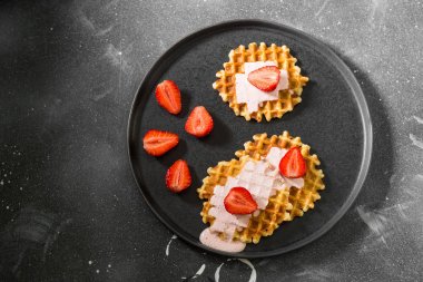 Karanlık bir arka planda siyah bir plaka üzerinde çilek ile waffle