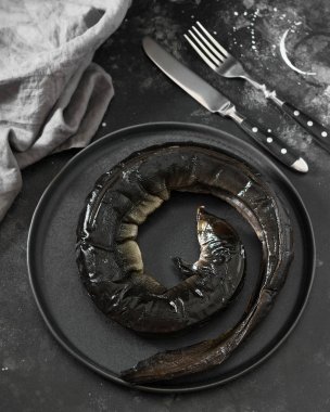 Karanlık bir arka planda siyah bir kase balık yılan balığı