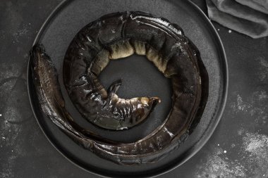 Karanlık bir arka planda siyah bir kase balık yılan balığı