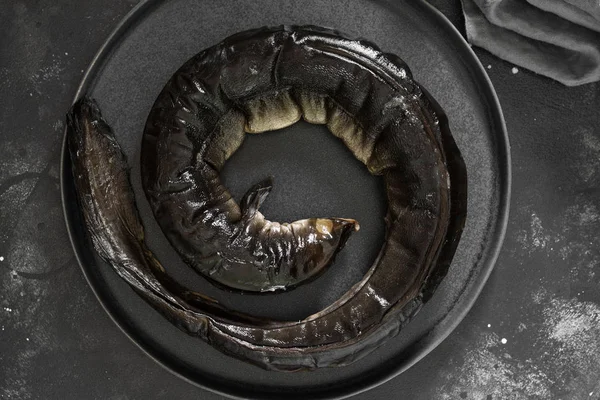 Karanlık bir arka planda siyah bir kase balık yılan balığı