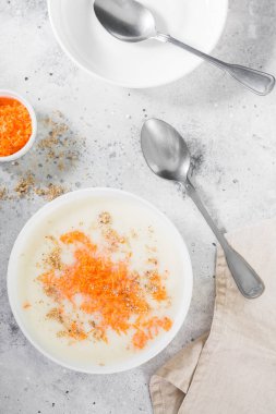 Hafif bir arka planda beyaz bir plaka içinde havuç ve ceviz ile irmik lapası