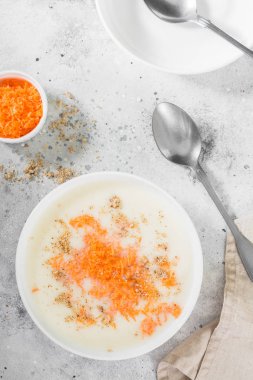 Hafif bir arka planda beyaz bir plaka içinde havuç ve ceviz ile irmik lapası