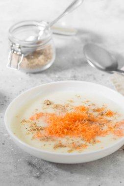 Hafif bir arka planda beyaz bir plaka içinde havuç ve ceviz ile irmik lapası