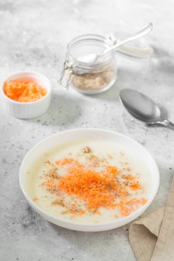 Hafif bir arka planda beyaz bir plaka içinde havuç ve ceviz ile irmik lapası