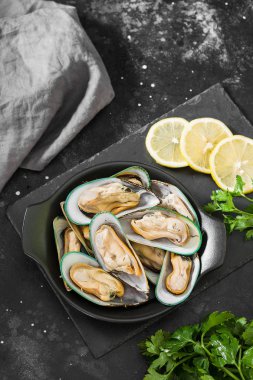 Koyu bir arka plan üzerinde siyah bir tabak ta ham kivi midye