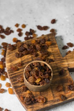 Hafif bir arka plan üzerinde ahşap bir kase içinde kuru üzüm