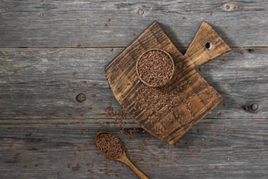 Gri ahşap bir masa üzerinde ahşap bir kase keten tohumu. Rustik stil