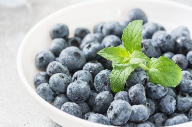 Hafif bir arka plan üzerinde beyaz bir kapta yaban mersini