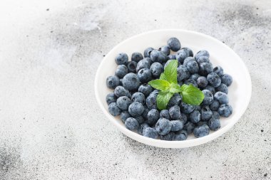 Hafif bir arka plan üzerinde beyaz bir kapta yaban mersini