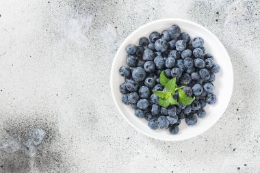 Hafif bir arka plan üzerinde beyaz bir kapta yaban mersini