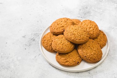 Hafif bir arka plan üzerinde beyaz bir tabakta yulaf ezmesi çerezleri