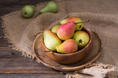 Tahta bir masanın üzerinde tahta bir kapta armut. Rustik stil