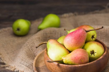 Tahta bir masanın üzerinde tahta bir kapta armut. Rustik stil