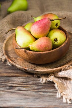 Tahta bir masanın üzerinde tahta bir kapta armut. Rustik stil