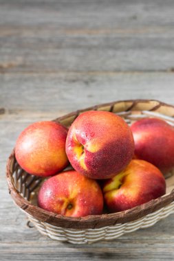 Gri ahşap arka plan üzerinde sepet sulu ve olgun nektarin