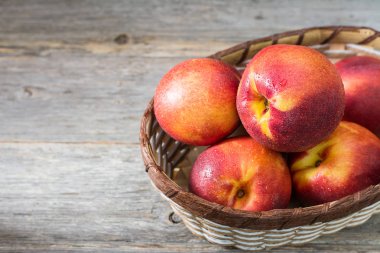 Gri ahşap arka plan üzerinde sepet sulu ve olgun nektarin