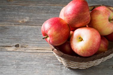 Elmalar gri ahşap arka plan üzerinde bir sepet içinde. Sonbahar hasadı