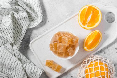 Açık gri bir masada beyaz bir seramik kasede şeker serpiştirilmiş marmelat.