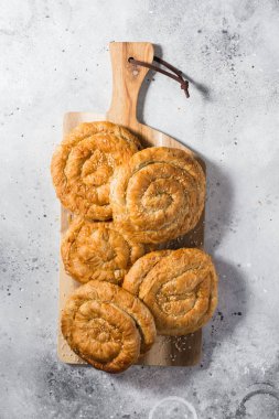 Açık gri mutfak masasında tahta tahtada çörekler. Üst görünüm