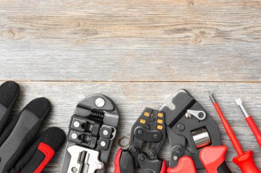 Gri ahşap bir masadaki elektrikçi ya da inşaatçının aletleri. İnşaat aletleri: masadaki kramponlar, tornavidalar, bıçak, eldivenler ve bant mezurası. Metin için boşluk olan üst görünüm