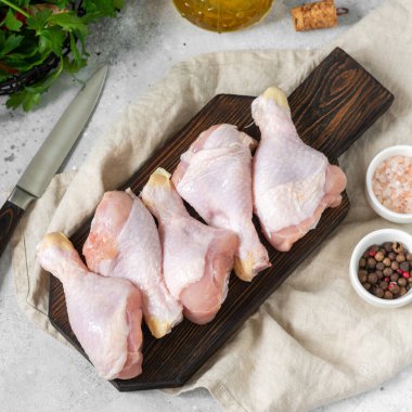 Açık gri mutfak masasındaki ahşap bir tahtada tavuk budu. Pişirme sürecinde çiğ tavuk budu. Tavuk budu. Yukarıdan görünüşü